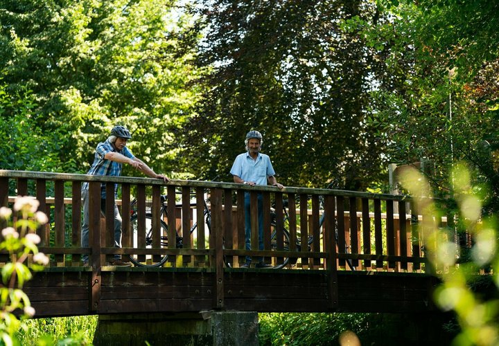 Zwei Personen bei einer Fahrradtour auf einer Brücke