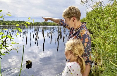 Zwei Personen schauen auf einen Waldsee